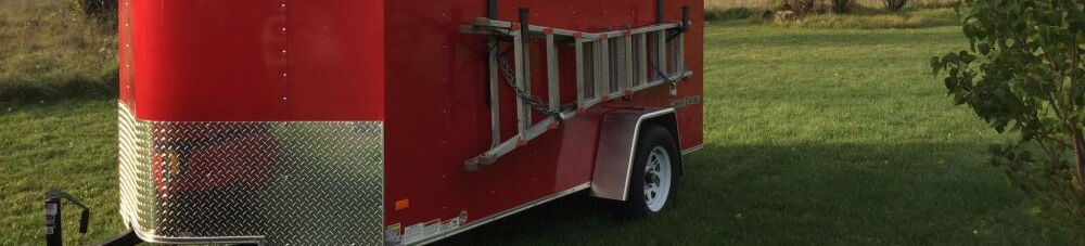 Red enclosed trailer parked on grass.