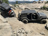 Black Jeep pulling trailer over large rocks.
