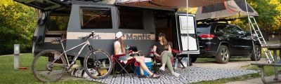 two women sitting outside a rv and talking.