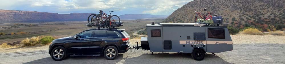 A car with a roof rack towing a camper with a trailer hitch