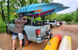 A person loading a roof rack with kayaks.
