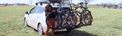 woman loading bike on hitch bike rack.