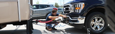 man hooking up truck to flat tow. 