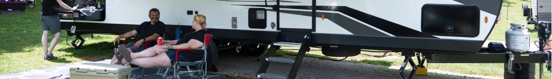 man and woman relaxing outside an rv.