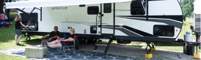 man and woman relaxing outside an rv.