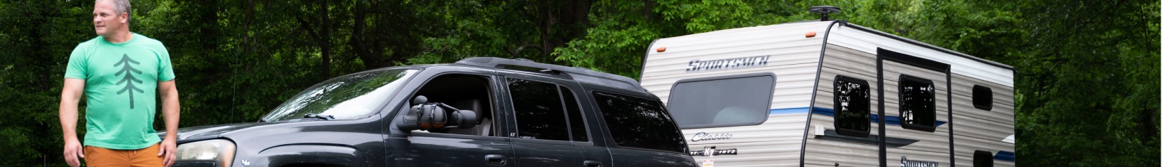 man standing by truck pulling travel trailer. 