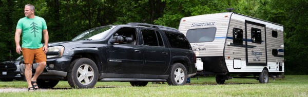 man standing by truck pulling travel trailer. 