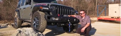 man working on winch on front of jeep.